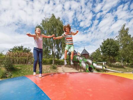 Kinder springen auf dem Lufttrampolin auf dem Spielplatz im Ferienpark Landal Warsberg