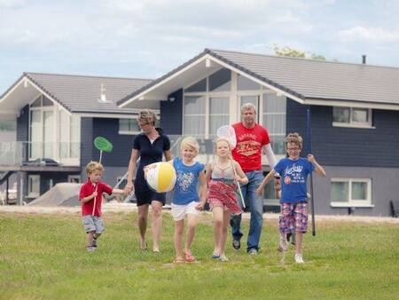 Familienspaziergänge auf einer Wiese vor Ferienhäusern im Landal Waterpark Sneekermeer