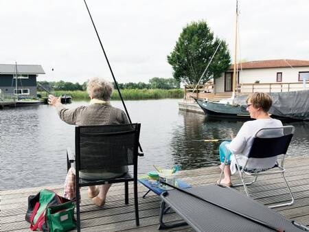 Mann fischt vom Steg seines Ferienhauses im Ferienpark Landal Waterpark Sneekermeer