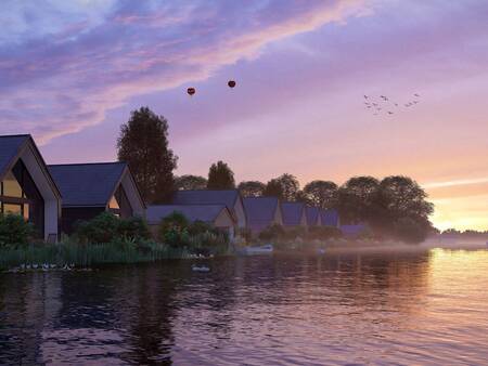 Ferienhäuser am Wasser bei Sonnenaufgang im Ferienpark Landal Waterresort Blocksyl