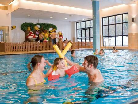 Eine Familie spielt im Wasser des Swimmingpools des Ferienparks Landal Winterberg