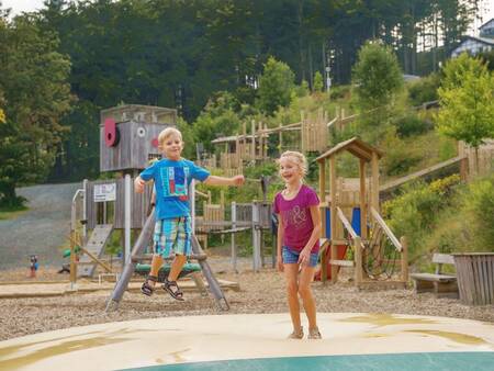 Kinder springen auf dem Lufttrampolin auf einem Spielplatz im Ferienpark Landal Winterberg