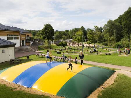 Kinder springen auf dem Lufttrampolin auf einem Spielplatz im Ferienpark Landal Wirfttal