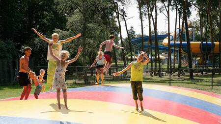 Kinder springen auf dem Lufttrampolin auf einem Spielplatz im Ferienpark Molecaten Bosbad Hoeven