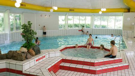 Die Leute schwimmen im Hallenbad mit Sprudelbad des Ferienparks Molecaten Park De Leemkule
