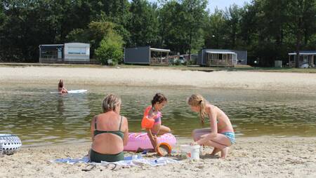 Familie spielt im Sand des Erholungssees im Ferienpark Molecaten Park Kuierpad