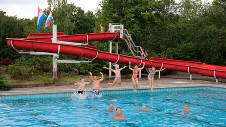 Menschen schwimmen im Außenpool mit Rutsche im Ferienpark Molecaten Park Kuierpad