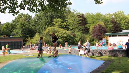 Kinder springen auf dem Trampolin im Schwimmbad des Molecaten Park Landgoed Ginkelduin