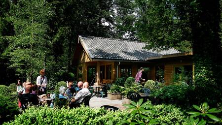 Menschen sitzen auf der Terrasse der Kantine des Ferienparks Molecaten Park Landgoed Molecaten