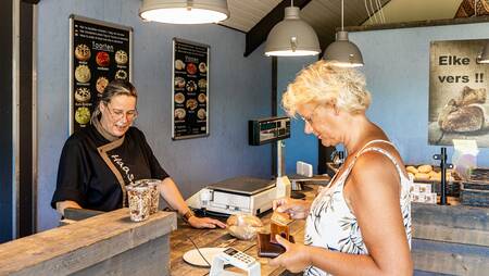 Eine Frau kauft Sandwiches in der Brotboutique im Ferienpark Molecaten Park Noordduinen