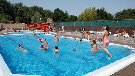 Menschen im Freibad mit großer roter Rutsche im Ferienpark Molecaten Park Rondeweibos