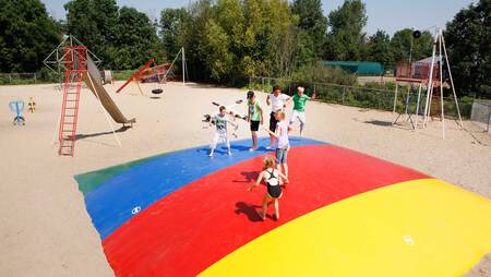 Kinder springen auf dem Lufttrampolin auf einem Spielplatz im Ferienpark Molecaten Park Rondeweibos