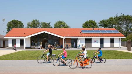 Kinder radeln vor dem Supermarkt des Ferienparks Molecaten Park Rondeweibos