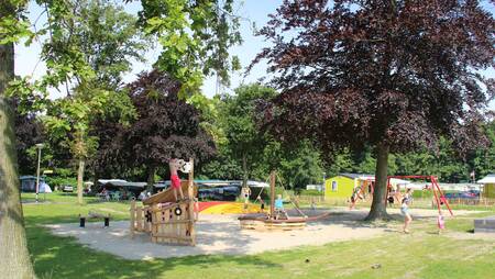 Kinder spielen auf einem Spielplatz zwischen den Chalets im Ferienpark Molecaten Waterbos