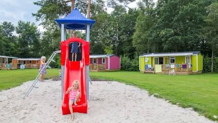 Kinder spielen auf einem Spielplatz zwischen den Chalets im Ferienpark Molecaten het Landschap