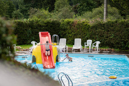 Kinder rutschen im Freibad des Ferienparks Petite Suisse die Rutsche hinunter