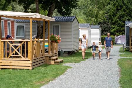 Eine Familie geht im Ferienpark RCN Belledonne auf einem Weg zwischen Mobilheimen spazieren