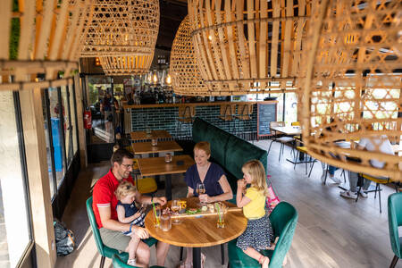 Die Familie sitzt im Restaurant des Ferienparks RCN Domaine de la Noguière