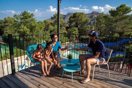 Die Familie sitzt auf der Terrasse am Außenpool des Ferienparks RCN Domaine de la Noguière