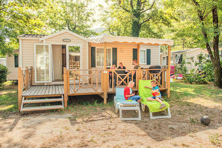 Familie im Garten eines Mobilheims im Ferienpark RCN La Bastide en Ardèche