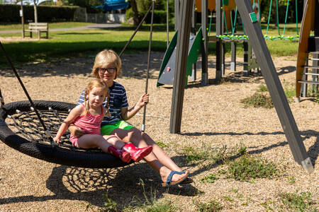 Kinder auf der Schaukel auf einem Spielplatz im Ferienpark RCN Le Moulin de la Pique