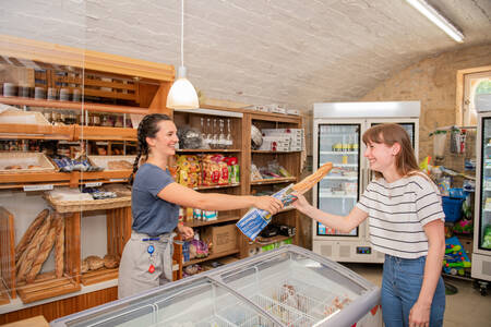 Frau kauft Baguette im Supermarkt des Ferienparks RCN Le Moulin de la Pique