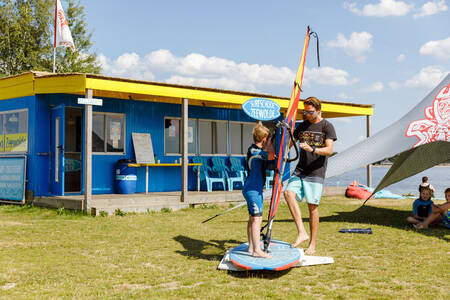 Kind auf einem Surfbrett in der Surfschule im Ferienpark RCN Zeewolde