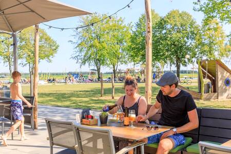 Paar isst auf der Terrasse der Brasserie 't Smokkelstrand im Ferienpark RCN de Flaasbloem