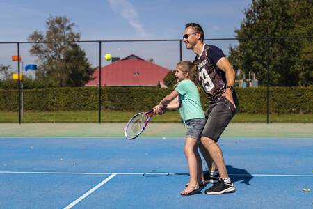 Vater und Tochter spielen Tennis auf dem Tennisplatz des Ferienparks RCN de Potten