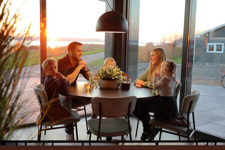 Familie am Tisch in einem Ferienhaus im Ferienpark RCN de Schotsman