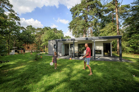Vater und Tochter spielen Tennis im Garten eines Ferienhauses im Ferienpark RCN het Grote Bos