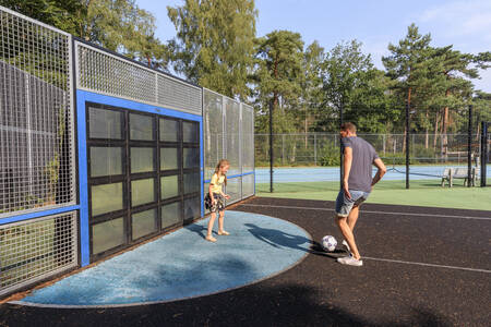 Vater und Tochter spielen Fußball auf dem Sportplatz des Ferienparks RCN het Grote Bos