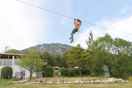 Mädchen auf einer Seilrutsche im Abenteuerpark des Ferienparks RCN Les Collines de Castellane