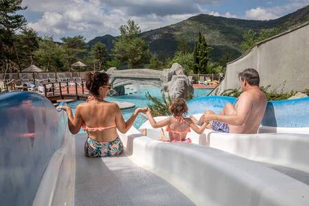 Familie rutscht eine Rutsche im Außenpool des Ferienparks RCN les Collines de Castellane hinunter