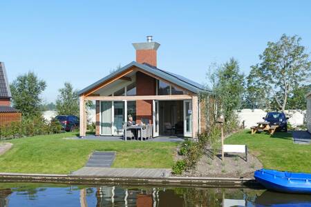 Eine Lounge im Garten eines Ferienhauses am Wasser im Recreatiepark Tusken de Marren