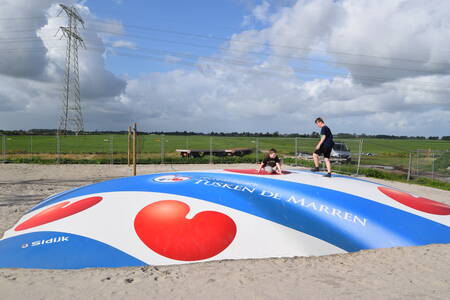 Kinder springen auf einem Lufttrampolin auf einem Spielplatz im Recreatiepark Tusken de Marren