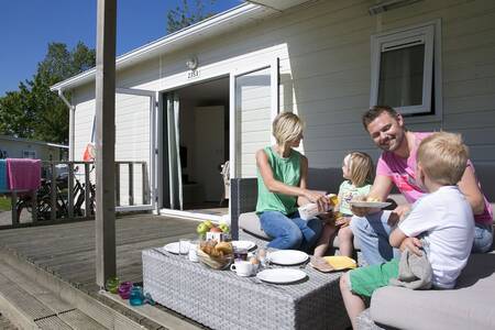 Familie beim Essen auf der Veranda eines Chalets im Ferienpark Roompot Beach Resort