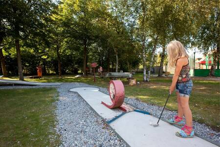 Mädchen spielt Golf auf dem Minigolfplatz des Ferienparks Roompot Bospark Lunsbergen