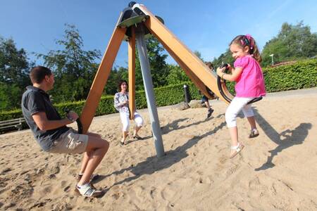 Eine Familie spielt auf einem Spielplatz im Ferienpark Roompot Bospark de Schaapskooi