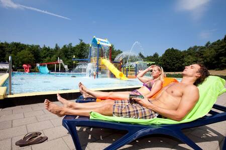 Menschen auf Liegestühlen am Außenpool des Ferienparks Roompot Buitenplaats De Hildenberg