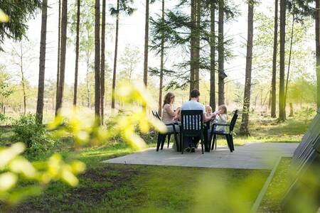 Familie beim Essen im Garten eines Ferienhauses im Roompot Bungalowpark Hoenderloo