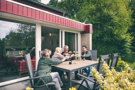 Die Leute trinken auf der Terrasse eines Ferienhauses im Roompot Bungalow Park Schin op Geul