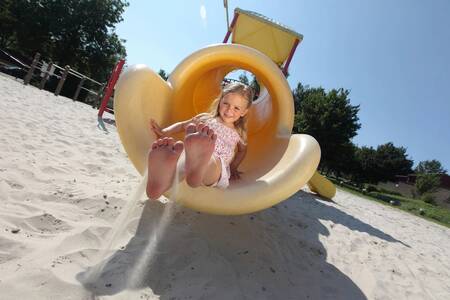 Kind auf der Rutsche auf dem Spielplatz des Ferienparks Roompot Bungalowpark Schin op Geul