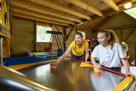 Mutter und Tochter spielen Airhockey im Ferienpark Roompot Château des Marais