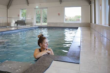 Eine Frau schwimmt im Hallenbad des Ferienparks Roompot De Heihorsten