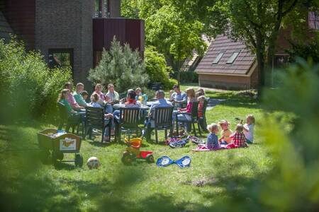 Familie sitzt im Garten eines Ferienhauses im Ferienpark Roompot De Katjeskelder