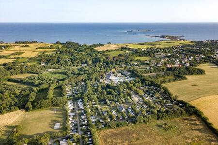 Luftaufnahme der Chalets im Ferienpark Roompot Deux Fontaines mit dem Meer am Horizont