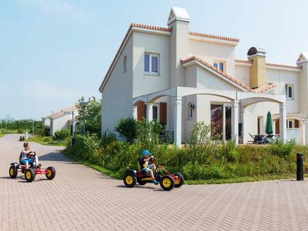 Kinder auf Go-Karts und ein Haus mit mediterranem Flair im Roompot Duinresort Dunimar