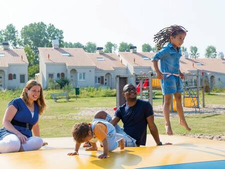Kinder springen auf dem Lufttrampolin auf einem Spielplatz im Ferienpark Roompot Duinresort Dunimar