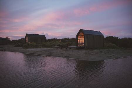 Ferienhäuser in der Abenddämmerung am kleinen Strand von Roompot ECO Grevelingen